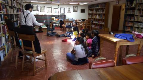 Un narrador cuenta historias a un grupo de niños en una biblioteca.