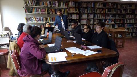 Un grupo de personas trabaja en computadoras portátiles en una biblioteca.