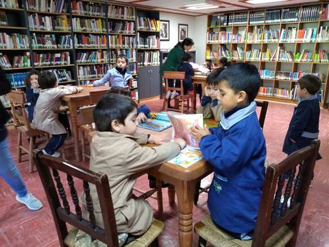 Un grupo de niños está aprendiendo y jugando en una biblioteca.