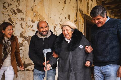 Un grupo de personas sonrientes se encuentra en un lugar con paredes desgastadas, mostrando alegría y camaradería.