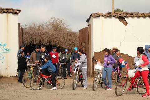 Un grupo de personas se reúne en un lugar al aire libre con bicicletas, algunos son niños y otros adultos.