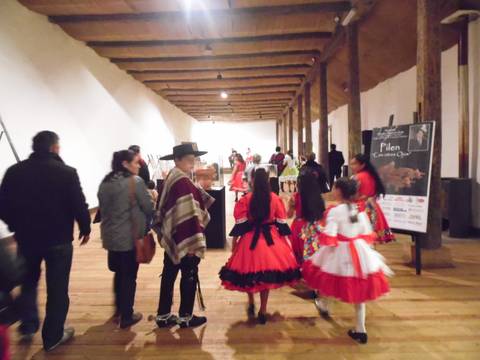 Un grupo de personas con vestimenta tradicional camina por un espacio interior con un ambiente festivo.