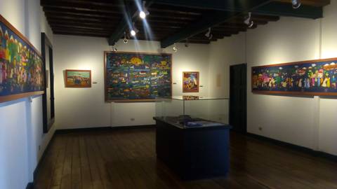 Interior de una galería de arte con varias pinturas coloridas en las paredes.