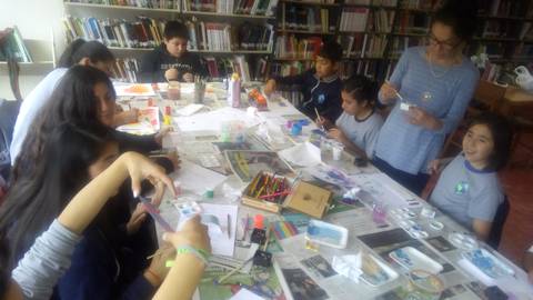 Un grupo de niños y adultos participan en una actividad de manualidades en una biblioteca.