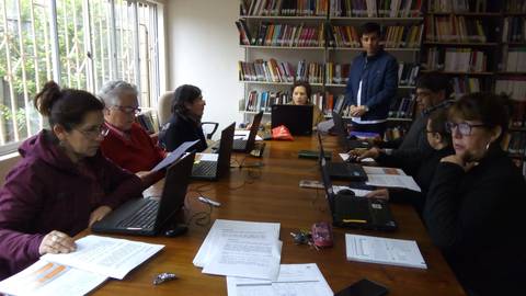 Un grupo de personas trabajando en laptops alrededor de una mesa en una biblioteca.