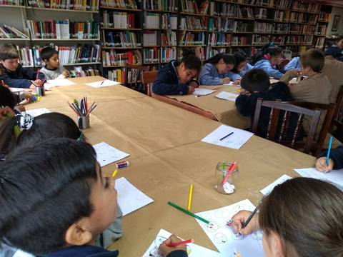 Un grupo de niños está dibujando en una biblioteca.