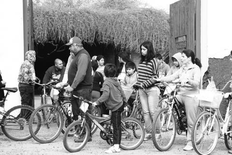 Un grupo de personas de diversas edades se congrega con bicicletas en un lugar exterior.