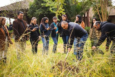 Un grupo de personas observa y participa en una actividad de siembra en un entorno natural.