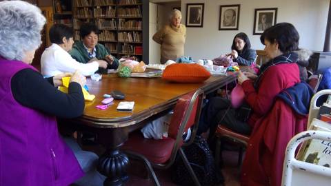 Un grupo de mujeres se reúne en una mesa para realizar manualidades.