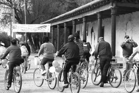 Un grupo de personas montando en bicicleta por un camino con casas de fondo.