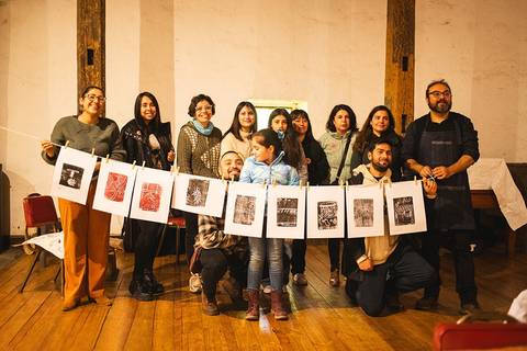 Un grupo de personas sonrientes posando juntas con una serie de impresiones colgadas delante de ellos.