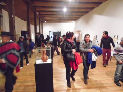 Una exposición con varias personas en un museo, destacando una pieza de cerámica en primer plano.