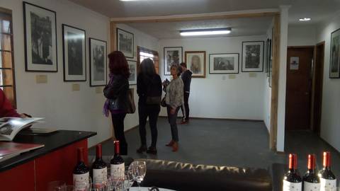 Una sala de exposición con varias personas mirando fotografías en las paredes.