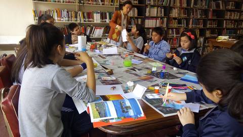 Un grupo de niños participan en una actividad de manualidades en una biblioteca.