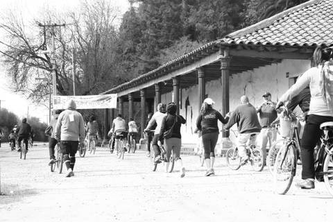 Un grupo de personas camina y monta en bicicleta por un camino junto a un edificio antiguo.