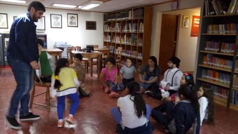 Un grupo de niños y adultos participan en una actividad en una biblioteca.
