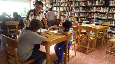 Un hombre ayuda a dos niños a estudiar en una biblioteca.