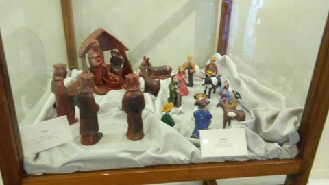 La imagen muestra un belén con figuras de cerámica en una vitrina.