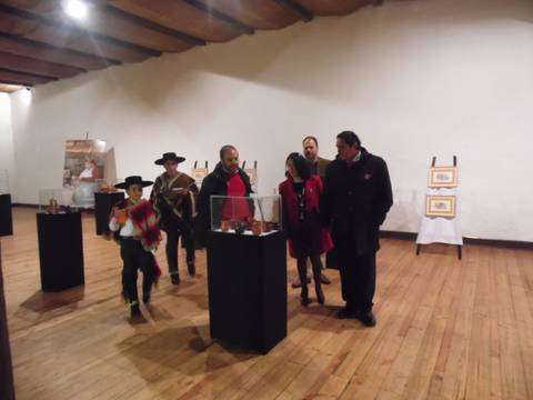 Un grupo de personas observa una exposición en un salón con muebles de madera.