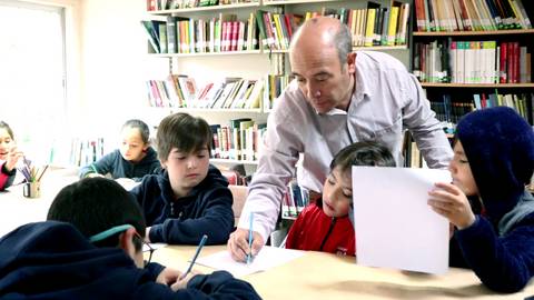 Un maestro enseña a un grupo de niños en una biblioteca.