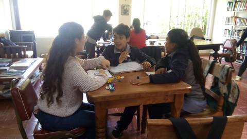 Un grupo de jóvenes está colaborando en una tarea en una biblioteca.
