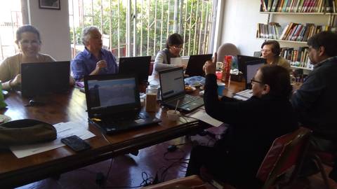 Un grupo de personas trabajando frente a computadoras en una mesa.