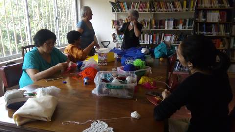 Un grupo de personas trabajando en manualidades en una mesa rodeada de libros.