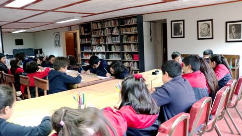 Un grupo de estudiantes está trabajando en mesas en una biblioteca.