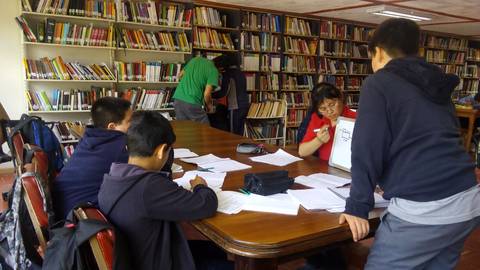 Un grupo de estudiantes se reúne en una biblioteca, trabajando en tareas y proyectos en un ambiente de estudio colaborativo.