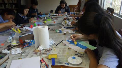 Un grupo de niños está pintando en una mesa llena de materiales de arte.