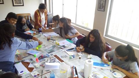 Un grupo de estudiantes participan en una actividad de pintura en una sala iluminada.