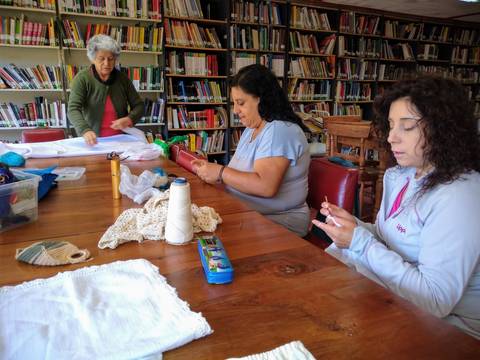 Un grupo de mujeres se reúne en una biblioteca para participar en una actividad de manualidades.