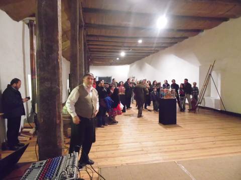 Una multitud reunida en un evento en un espacio interior con piso de madera.