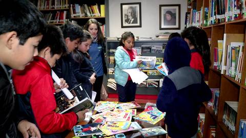 Un grupo de niños explora y revisa libros y revistas en una biblioteca.