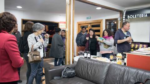 Un grupo de personas interactuando y socializando en un espacio interior con comida y bebida.