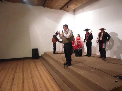 Una banda musical se presenta en un escenario con un cantante y varios instrumentos en un ambiente festivo.