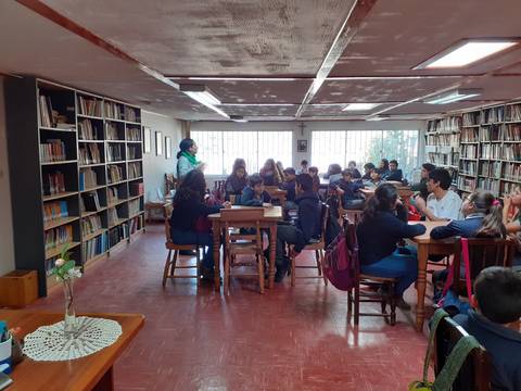 Un grupo de estudiantes está trabajando en una biblioteca rodeada de estanterías llenas de libros.