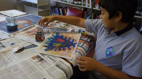 Un niño está pintando un dibujo colorido sobre una mesa con periódicos.
