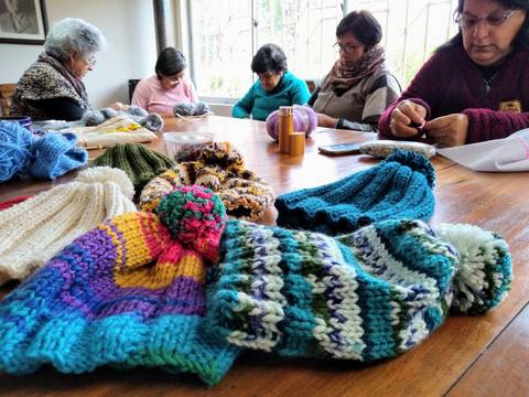 Un grupo de mujeres está tejiendo gorros coloridos en un taller comunitario.