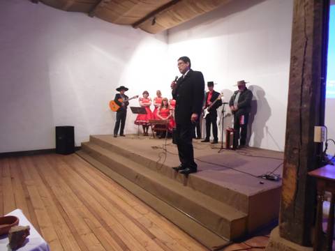 Un grupo de músicos actuando en un escenario con un cantante al frente y varios instrumentos musicales.