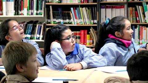 Un grupo de niños en una biblioteca escuchando atentamente.