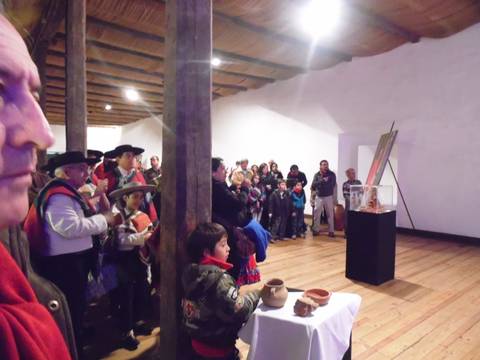 Una multitud observa y participa en un evento cultural con objetos de cerámica en un espacio cerrado.