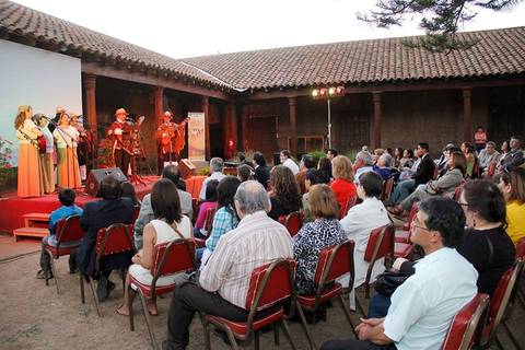 Un evento cultural al aire libre con un grupo de músicos actuando frente a una audiencia sentada.
