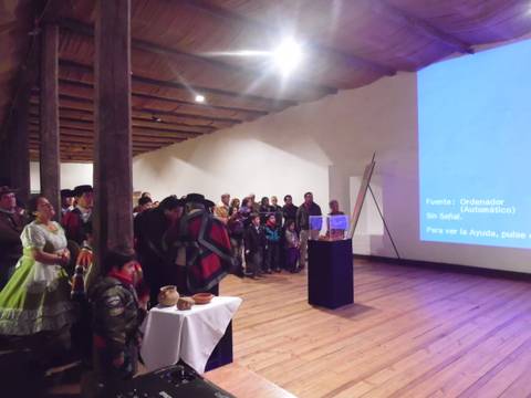 Un grupo de personas asiste a una presentación en un ambiente con madera expuesta y luces suaves.