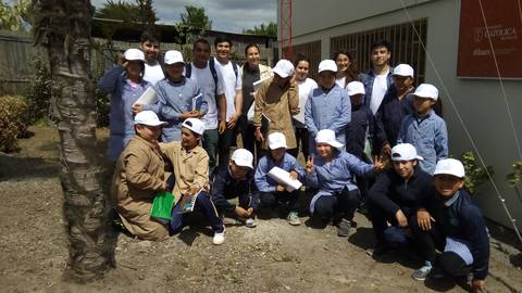 Un grupo de estudiantes y adultos sonríen juntos en un día soleado en un espacio al aire libre.
