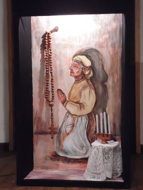 Una pintura de una figura femenina rezando con rosario en un entorno sencillo.