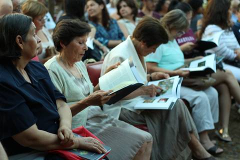 Un grupo de mujeres sentadas en un evento, revisando libros o documentos.