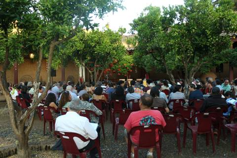 Un grupo de personas asiste a un evento al aire libre, rodeados de árboles y plantas.