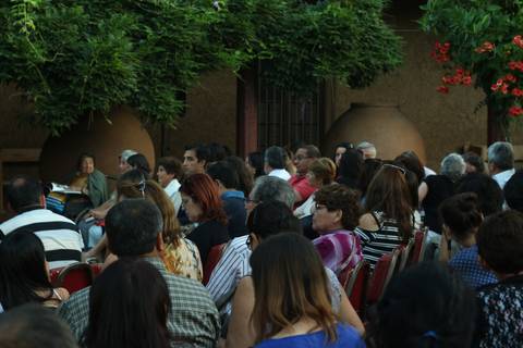 Un grupo de personas sentadas en un evento al aire libre, con un entorno natural y adornos florales.