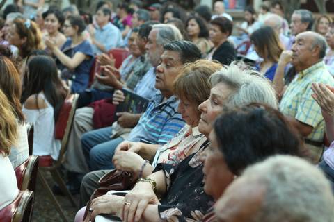 Una multitud de personas sentadas en un evento, mostrando diversas expresiones de atención y emoción.